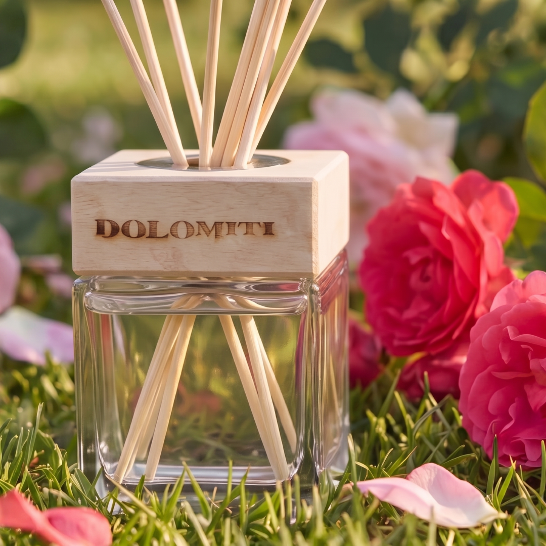 Diffusore alla rosa di altura sull'erba tra rose e petali