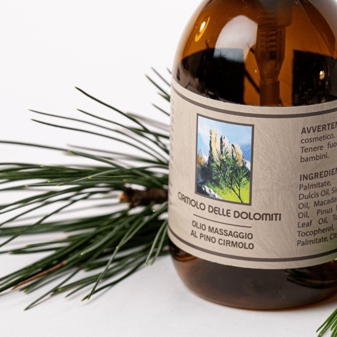Dettaglio dell'olio da massaggio al pino cirmolo tra aghi di pino