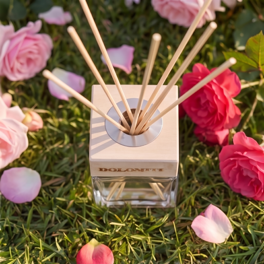 Diffusore alla rosa di altura sull'erba con petali attorno
